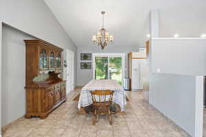Dining room featuring a chandelier, vaulted ceiling, and light tile patterned floors