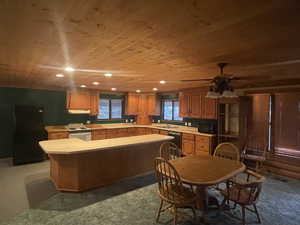 Kitchen with wooden ceiling, light countertops, black appliances, a center island, and brown cabinetry