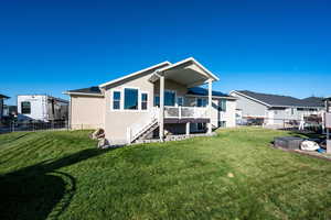 Rear view of house featuring a fenced backyard, stairway, stucco siding, and a deck