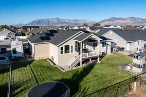 Rear view of property featuring a fenced backyard, a residential view, a shingled roof, stucco siding, and a deck with mountain view