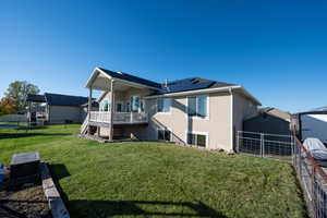 Rear view of property featuring a fenced backyard, stucco siding, roof mounted solar panels, stairs, and deck