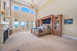 Bedroom with access to exterior, a chandelier, carpet, multiple windows, and a high ceiling