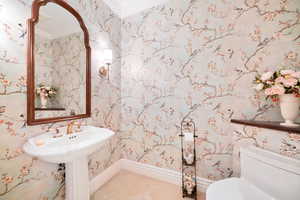 Bathroom with wallpapered walls, ornamental molding, and tile patterned floors