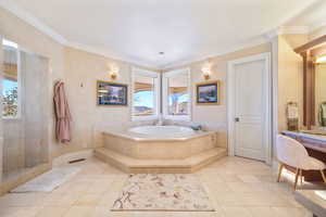 Bathroom with crown molding, a garden tub, light tile patterned floors, and vanity