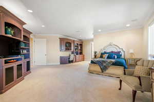 Bedroom featuring recessed lighting, crown molding, light colored carpet, and built in study area