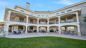 Back of house with a balcony, a chimney, a patio area, and brick siding