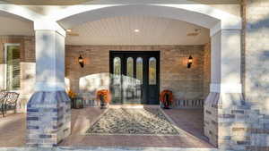 Property entrance featuring brick siding and a porch