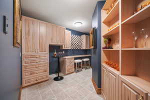 Kitchen with built in desk, light tile patterned flooring, light brown cabinetry, and light countertops