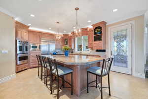 Kitchen featuring a kitchen breakfast bar, a center island, light stone countertops, backsplash, and hanging light fixtures