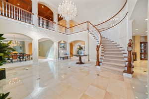 Entryway with a chandelier, stairs, a towering ceiling, arched walkways, and recessed lighting