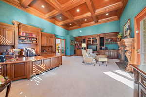 Office area featuring a towering ceiling, a fireplace, coffered ceiling, crown molding, and light carpet