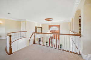 Hallway with a chandelier, crown molding, an upstairs landing, and carpet flooring