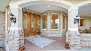 View of exterior entry featuring brick siding and covered porch