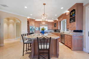 Kitchen featuring open shelves, arched walkways, a kitchen island, decorative light fixtures, and a kitchen breakfast bar