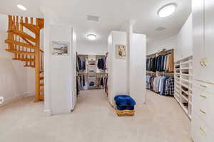 Walk in closet with light colored carpet