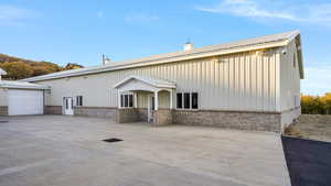View of front of house with brick siding, a chimney, a garage, a metal roof, and driveway