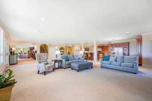 Living area featuring ornamental molding, light colored carpet, arched walkways, recessed lighting, and stairs