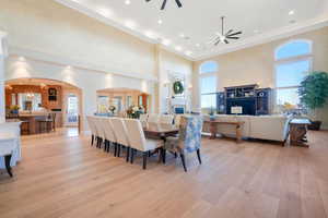 Dining area with arched walkways, a high ceiling, a chandelier, light wood finished floors, and a fireplace