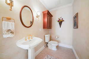Half bath featuring crown molding and light tile patterned floors