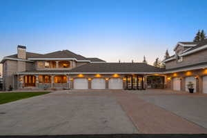 View of front of house with concrete driveway, an attached garage, a chimney, and a porch