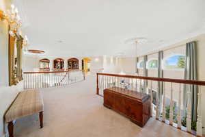 Sitting room featuring an upstairs landing, carpet flooring, a chandelier, and ornamental molding