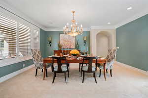 Dining space with crown molding, light carpet, a chandelier, and recessed lighting