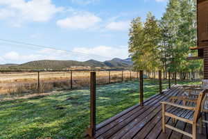 Wooden terrace featuring a mountain view, a fenced backyard, and a view of rural / pastoral area