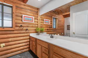 Half bath with vanity, beamed ceiling, and rustic walls