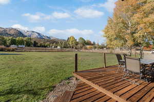 Wooden terrace with a fenced backyard, a rural view, outdoor dining space, and a mountain view