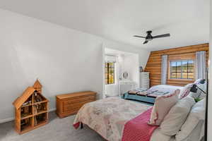 Carpeted bedroom with rustic walls and ceiling fan