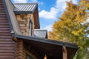 View of property exterior featuring stone siding, log exterior, and a metal roof