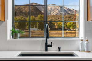 Kitchen view of a mountain backdrop, backsplash, and light stone counters