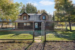 View of front of property featuring a gambrel roof, a porch, a metal roof, a gate, and a chimney