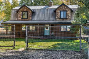 View of front of property with a metal roof, a chimney, a front yard, and a porch