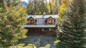 View of front facade with a chimney, a porch, a metal roof, a gate, and a fenced front yard