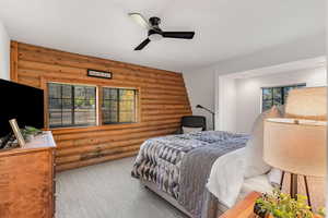 Bedroom with rustic walls, carpet flooring, and ceiling fan