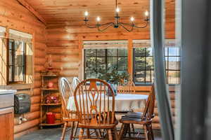 Dining space featuring wooden ceiling, plenty of natural light, log walls, and a chandelier