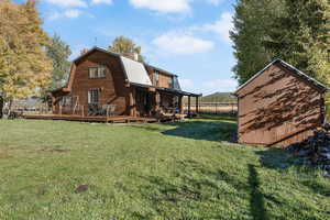 Back of property featuring a gambrel roof, a shed, log exterior, a chimney, and a deck