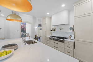 Kitchen featuring light stone counters, arched walkways, stainless steel gas cooktop, decorative backsplash, and recessed lighting