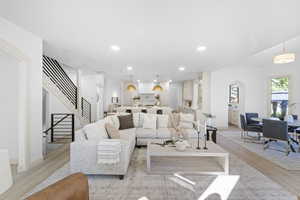 Living room with arched walkways, light wood-type flooring, and recessed lighting