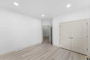 Unfurnished bedroom with light wood-type flooring, recessed lighting, and a closet