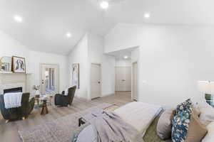 Bedroom featuring high vaulted ceiling, wood finished floors, a glass covered fireplace, ceiling fan, and recessed lighting
