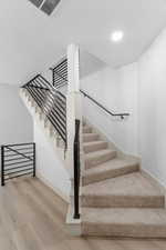 Stairway featuring wood finished floors and recessed lighting