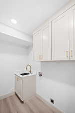 Laundry area featuring cabinet space, light wood-type flooring, hookup for a washing machine, electric dryer hookup, and recessed lighting