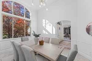 Dining space with arched walkways, plenty of natural light, a chandelier, ornamental molding, and a high ceiling