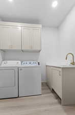 Washroom featuring cabinet space, light wood finished floors, and washer and clothes dryer