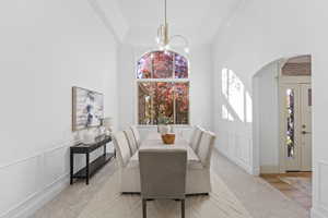 Dining space featuring a decorative wall, plenty of natural light, arched walkways, a chandelier, and carpet