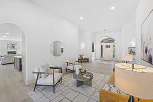 Living room featuring light wood-type flooring, recessed lighting, arched walkways, and a fireplace