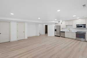 Kitchen featuring stainless steel appliances, white cabinetry, recessed lighting, light countertops, and light wood-style floors