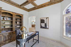 Office space featuring light colored carpet, coffered ceiling, arched walkways, beamed ceiling, and a towering ceiling